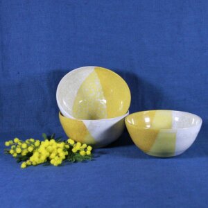 des bols jaune et blanc en céramique, posés devant un fond bleu roi