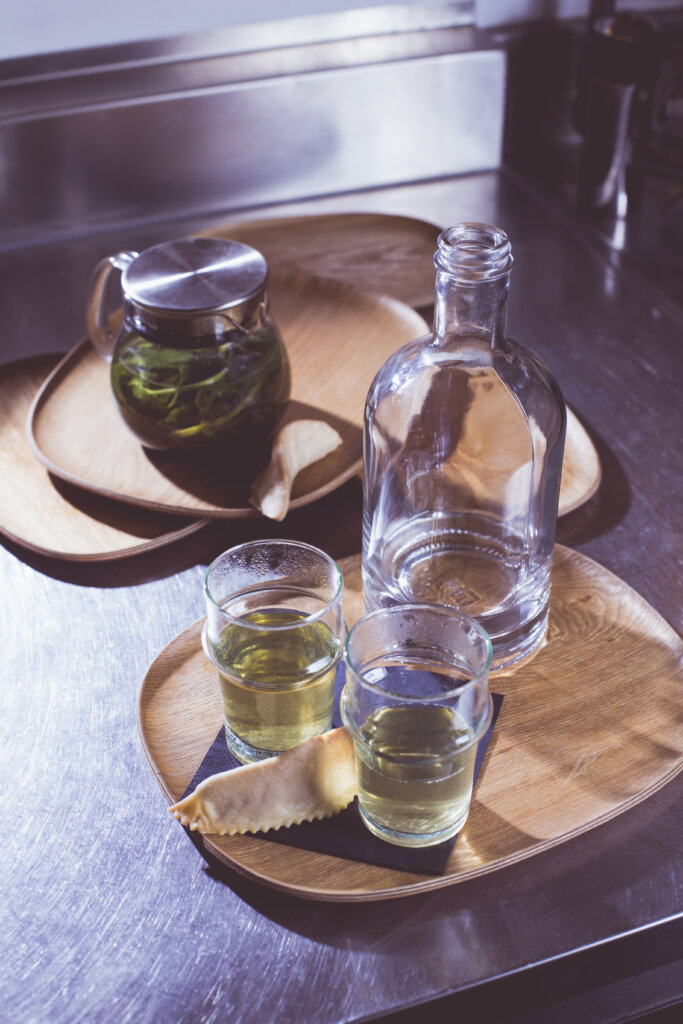 vue en plongée d'une théière de thé à la menthe servi dans des verres placés sur des plateaux et accompagnés d'une corne de gazelle.